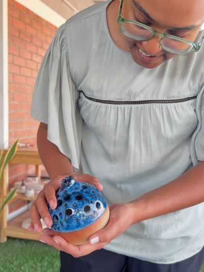 A student admiring her unique, hand-built creation after it has been glaze-fired. The blue and black glaze created a beautiful, speckled effect.