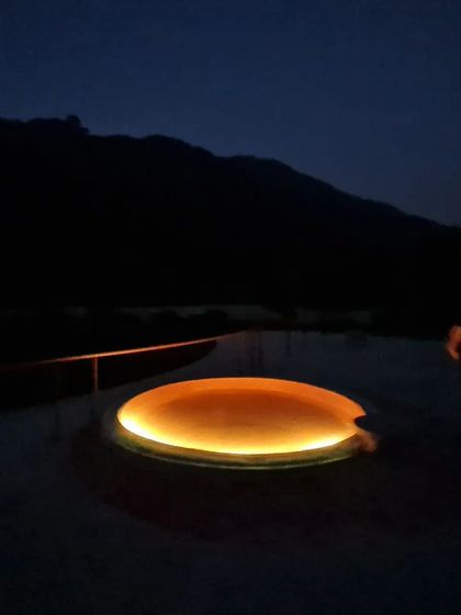 A circular skylight on the terrace glows like a 'Night Sun'. This feature transforms the roof into a celestial map, bringing a touch of warmth and magic to the space after dark and interacting with the mountain's silhouette.