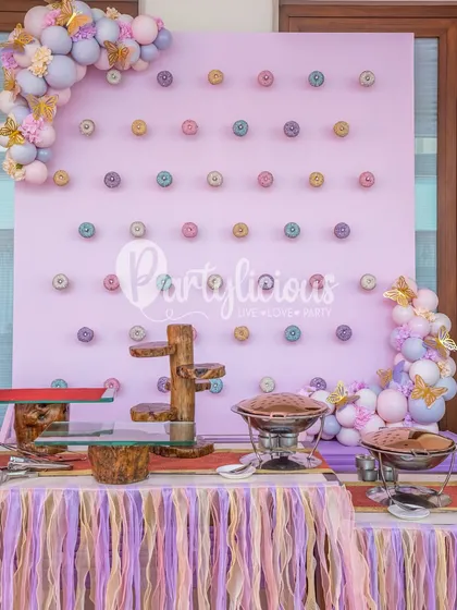 A donut wall is always a good idea! For this pastel-themed party, we created a custom wall to display treats, framed by a delicate balloon arrangement with butterfly accents.