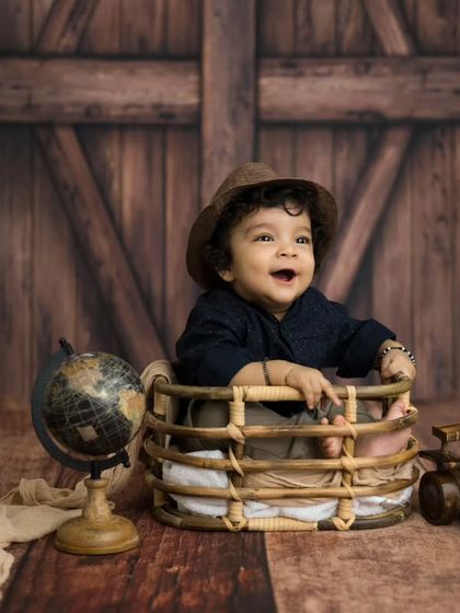 A classic portrait of a happy baby boy. His smile and the warm, wooden backdrop create a timeless and heartwarming image.