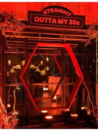 Milestone birthdays deserve a grand entrance. I designed this 'Straight Outta My 30s' entryway with dramatic red lighting, a custom sign, and a geometric swing installation that served as the perfect photo opportunity for the guest of honor and their friends.