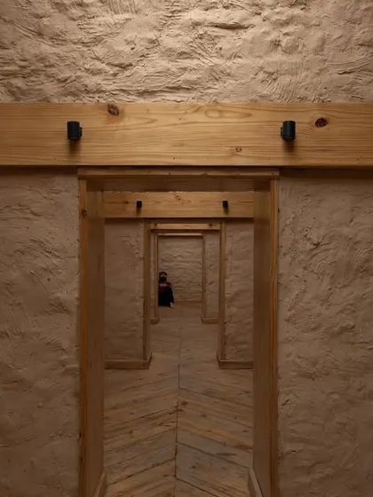 Inside the Rung Community Museum, a perspective of repeating doorways framed by local pine wood and textured mud-plastered walls creates a journey through the restored space, honoring its past.