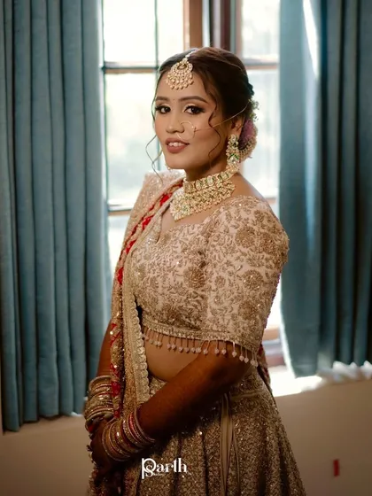 A portrait of the bride by the window, looking elegant in her pastel lehenga.