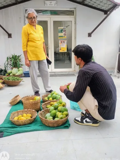 An elderly customer interacting with a young farmer, showing the intergenerational connections at the market.