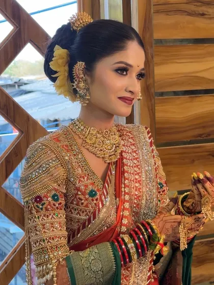 A candid shot of the bride in her orange and green Paithani, holding a 'khalbatta'.