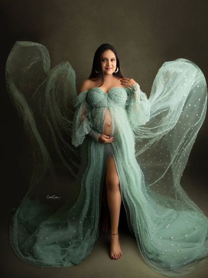 A full-body shot showcasing the incredible wing-like effect of this flowing green gown. The mom-to-be looks absolutely ethereal.