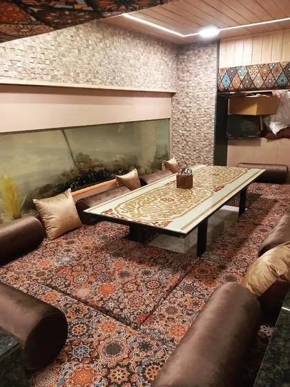 My Dastarkhwan seating area next to a large aquarium, offering a unique and relaxing dining environment. It's a perfect spot for a memorable family dinner.