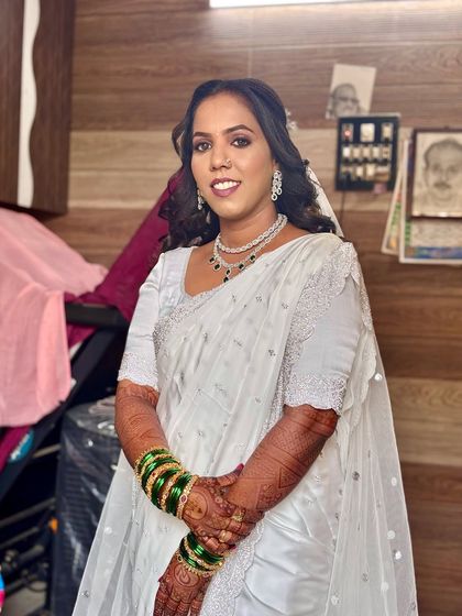 This Buddhist bride is wearing a beautiful white saree with green bangles. Her hair is styled in soft waves, creating a look of simple elegance.