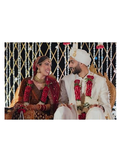 A happy, candid moment between the bride and groom. The contrast of their traditional attire against the modern floral backdrop creates a beautiful visual that reflects their personalities.