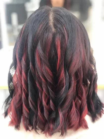 Adding highlights is a great way to create dimension. Here, I've woven striking red streaks through dark hair and finished with soft curls to really show off the contrast and movement in the style. This is a great option for a bold yet elegant change.