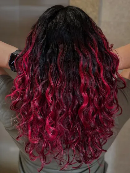A still shot of the fiery pink look, showing how vibrant color can look on well-defined, healthy curls. The contrast with the dark roots makes the pink pop.
