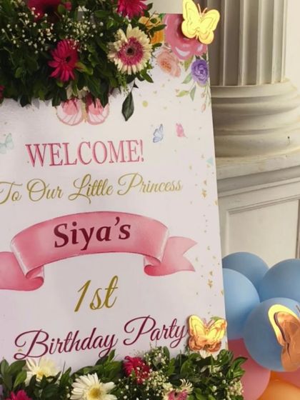 A beautiful welcome sign for a butterfly-themed first birthday party, decorated with fresh flowers and butterfly cutouts for an elegant touch.