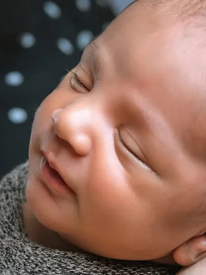 A close-up of a newborn's face, showing their peaceful sleep. The focus is entirely on the baby, with no distracting props.