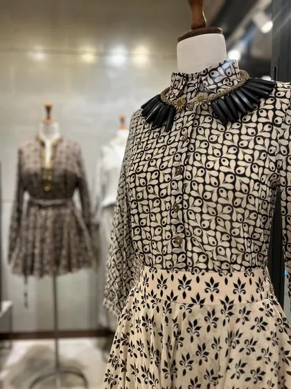 A detailed shot of the printed peplum top and skirt, paired with a bold, black collar necklace for a dramatic and stylish effect.