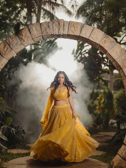 This image blends vibrant ethnic fashion with a touch of magic. The movement of the lehenga, the stone archway, and the atmospheric smoke create a captivating scene for a designer lookbook or campaign.