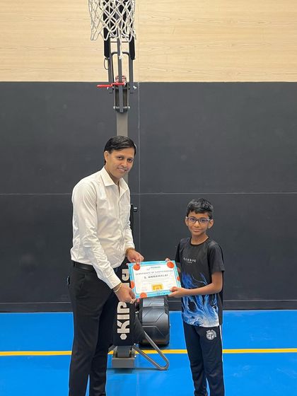 A young player proudly holds his certificate from our summer camp. Every milestone is worth celebrating.
