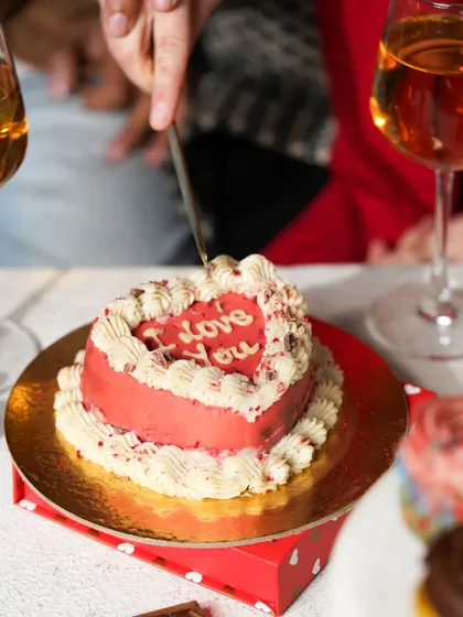 A close-up of a couple cutting into a heart-shaped "I Love You" cake, a perfect moment of celebration.
