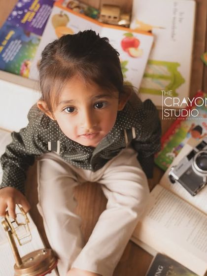 An overhead shot of the little explorer surrounded by books, a toy plane, and a vintage camera.