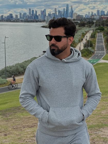 A close-up of our signature grey flared unisex tracksuit hoodie, highlighting its soft fabric and comfortable fit against a city skyline.