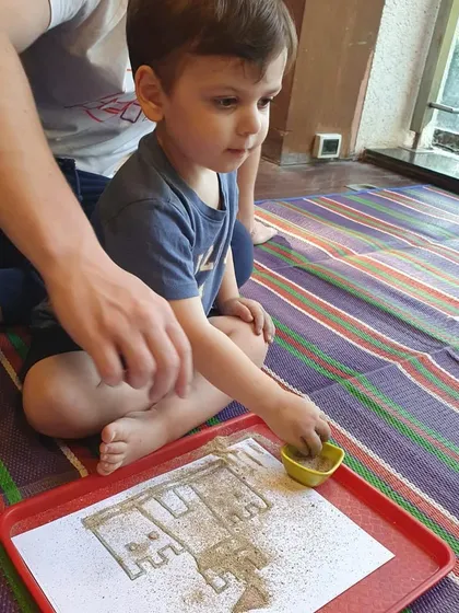 This young boy is focused on his sand castle art, using a small scoop to add sand. It’s a calm and engaging sensory activity.