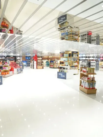 A very wide shot of the duty-free floor, showing the spacious aisles and ceiling architecture. This minimalist composition emphasizes the clean, modern environment of the airport shopping experience.