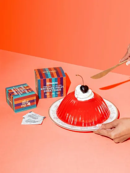 This shot uses a bold, warm color palette to create a fun and appetizing scene. The composition guides the eye from the product boxes to the final dessert, with the action of the knife adding a sense of anticipation.