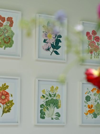 A close-up of framed floral artworks that hang on the walls. These pieces, created by the artist in the family, echo the blooms from the garden, bringing nature inside in a very personal way.