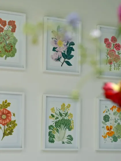 A close-up of framed floral artworks that hang on the walls. These pieces, created by the artist in the family, echo the blooms from the garden, bringing nature inside in a very personal way.