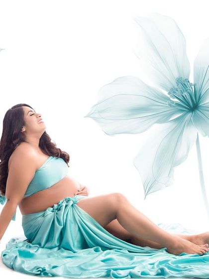 A beautiful bare-bump shot with the client wrapped in flowing turquoise fabric. The addition of illustrative flowers creates a fresh, artistic, and modern maternity portrait.