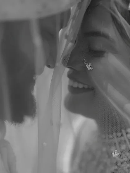 A soft and romantic black and white portrait of a couple under the bride's veil, creating a sense of intimacy and privacy.