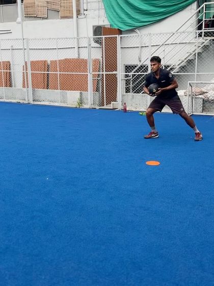 A tennis player performing a weighted medicine ball lateral shuffle. This drill is designed to improve court speed and the ability to decelerate and re-accelerate, crucial for reaching optimal hitting positions.