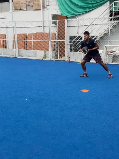 A tennis player performing a weighted medicine ball lateral shuffle. This drill is designed to improve court speed and the ability to decelerate and re-accelerate, crucial for reaching optimal hitting positions.