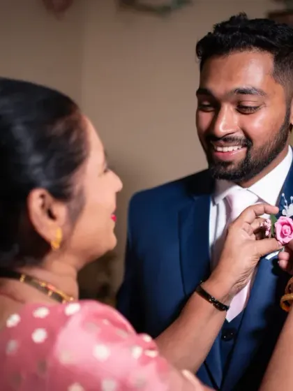 A touching moment between the groom and his mother as she pins on his boutonnière. These are the family memories that matter.
