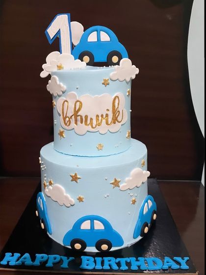 A two-tiered car-themed cake is perfect for a little boy's first birthday. This design features a soft blue frosting, fluffy clouds, and cute blue cars, creating a dreamy and playful cake for a milestone celebration.