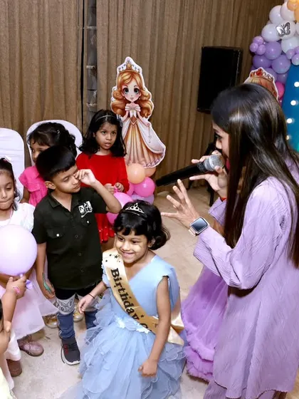 A game host engaging with children at a princess-themed birthday party, showing how we can include entertainment to keep the little ones happy.