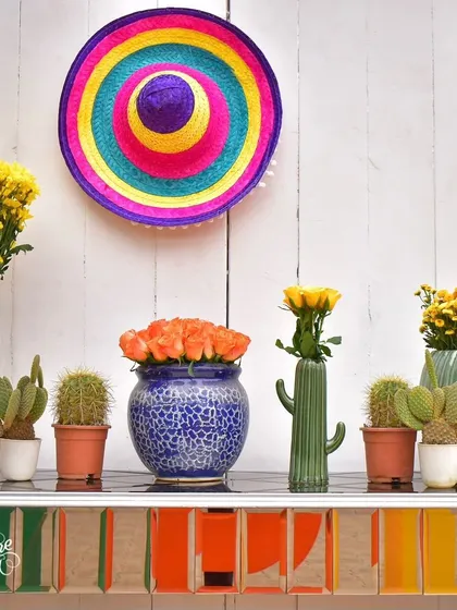 A detail shot of a shelf display, featuring a colorful sombrero, potted cacti, and flower arrangements in various vases.