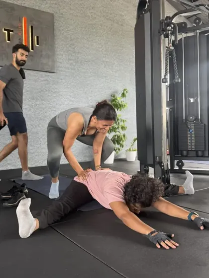 A great teacher knows when to guide and when to let you explore. Here, I am assisting a student in Upavishta Konasana, helping her find a deeper opening in her hips safely. My classes are a space for supported growth, and sometimes, a little bit of playfulness.