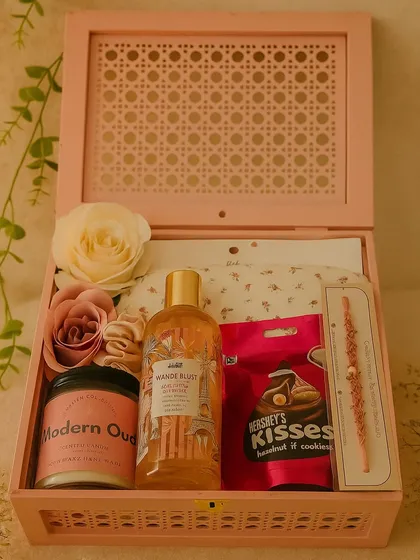 The perfect sisterhood box for Rakhi. This pink wooden box is filled with a full-size candle, Nykaa shower gel, an H&M eye mask, Hershey's Kisses, a scrunchie, and a beautiful rakhi.
