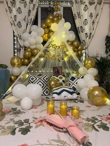 A closer look at the romantic bed canopy setup, showing the details of the fairy lights and the elegant white and gold balloons.