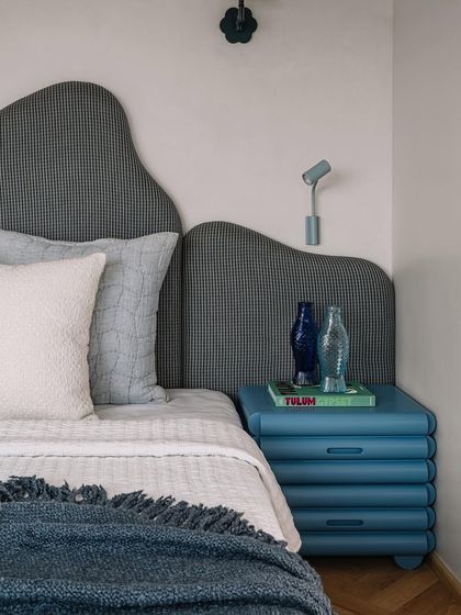 The master bedroom's custom bedside table and wavy headboard create a serene and stylish sleeping space.