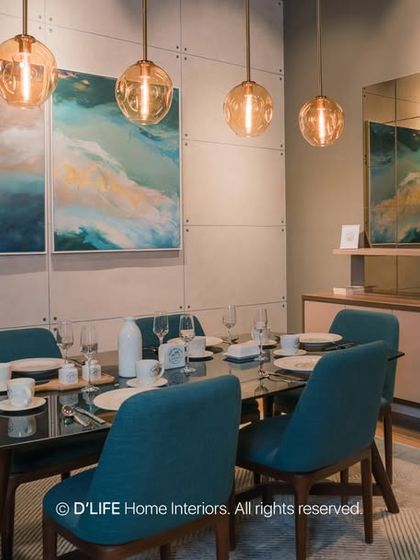 This dining area features bold teal chairs that add a vibrant pop of color against a neutral, textured wall. The mirrored sideboard and pendant lights add a touch of glamour.