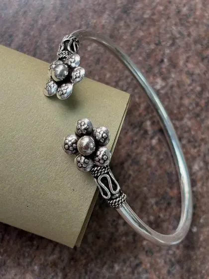 This adjustable silver cuff bracelet features a lovely floral design at each end. It's a simple yet elegant piece that can be easily adjusted for a perfect fit.