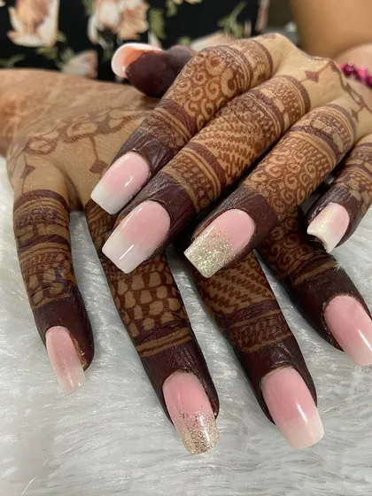 A classic baby boomer or ombré French manicure, perfect for a bride. The seamless blend from a soft pink base to a white tip on these long coffin nails creates a timeless and sophisticated look against the henna.