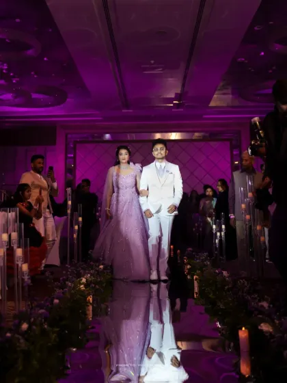 The couple's grand entrance down a mirrored aisle, reflecting the purple-lit glamour of their reception hall.