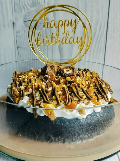 The perfect birthday cake for a chocolate and hazelnut fan. The golden 'Happy Birthday' topper adds a touch of elegance to this decadent Choco Rocher Tres Leches.