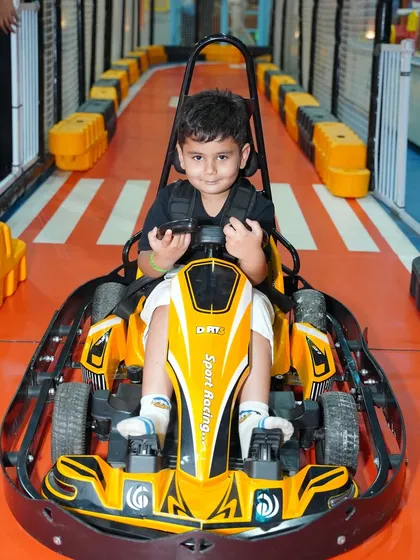 A joyful expression from a young boy in a yellow go-kart. The thrill of driving is a memory he won't soon forget.