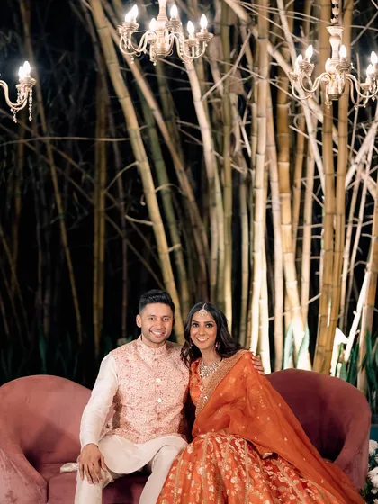 A quiet moment for the couple amidst their Sangeet celebration. The backdrop of bamboo and chandeliers creates a unique blend of natural and glamorous elements.