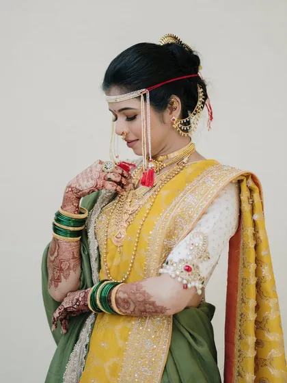 A demure and graceful portrait of a Marathi bride. Her downward glance and delicate hand gesture create a sense of timeless elegance and modesty.