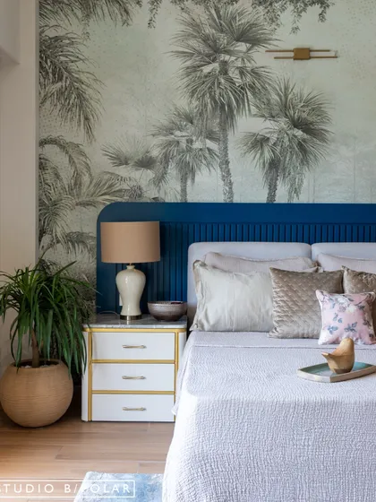A close-up of the bedside, showing the fluted detail on the headboard and the elegant combination of the blue with the white and gold nightstand.