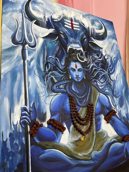 An angled view of the Mahadev painting, showing the texture of the canvas and the depth of the colors. The lighting highlights the details on his Trishul and the Rudraksha beads.